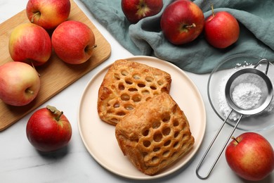 Photo of Delicious puff pastries with apples on white wooden table, flat lay