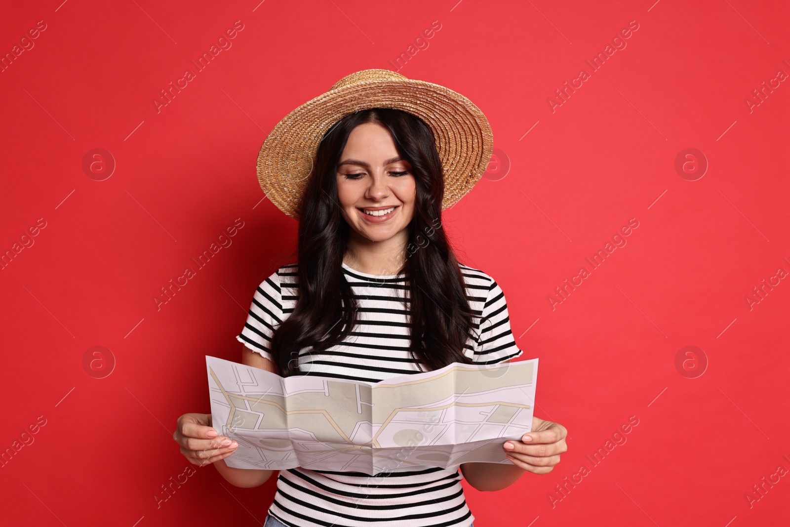 Photo of Young tourist in hat with map on red background