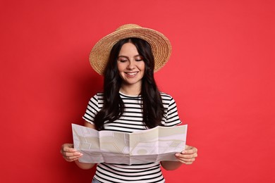 Photo of Young tourist in hat with map on red background