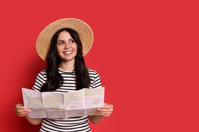 Young tourist in hat with map on red background, space for text