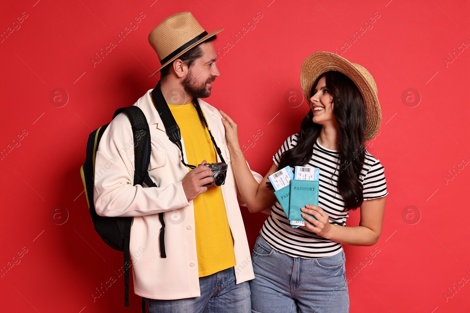 Photo of Tourism. Happy couple in hats with camera, passports and tickets on red background