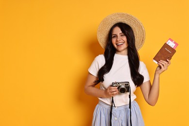 Photo of Young tourist in hat with camera, passport and ticket on yellow background, space for text