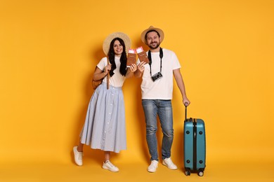 Photo of Tourism. Happy couple in hats with suitcase, passports and tickets on yellow background