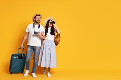 Photo of Tourism. Happy couple in hats with suitcase and binoculars on yellow background, space for text