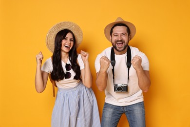 Tourism. Emotional couple in hats with camera on yellow background