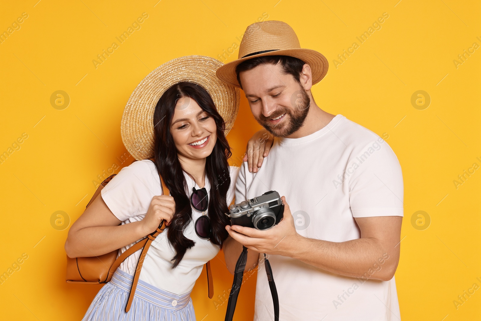 Photo of Tourism. Happy couple in hats with camera on yellow background