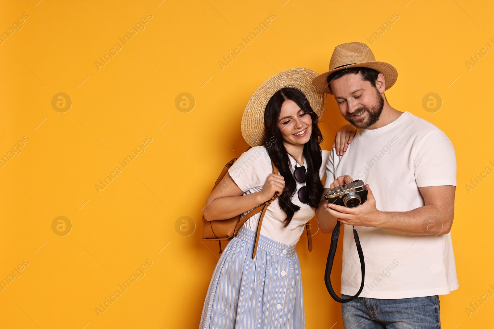 Photo of Tourism. Happy couple in hats with camera on yellow background, space for text