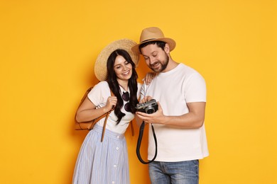 Photo of Tourism. Happy couple in hats with camera on yellow background