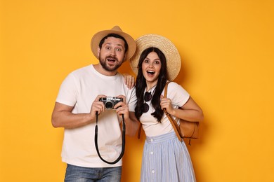 Photo of Tourism. Emotional couple in hats with camera on yellow background