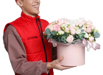 Photo of Smiling delivery man holding gift box with beautiful floral composition on white background, closeup