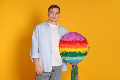 Photo of Happy man with colorful pinata on yellow background