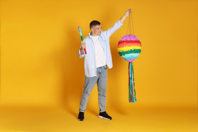 Happy man breaking pinata on yellow background