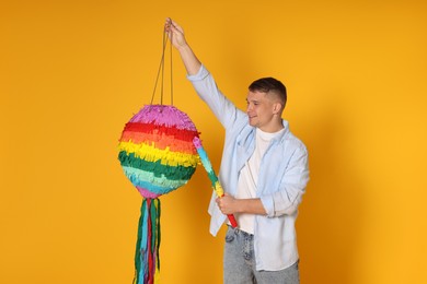 Happy man breaking pinata on yellow background