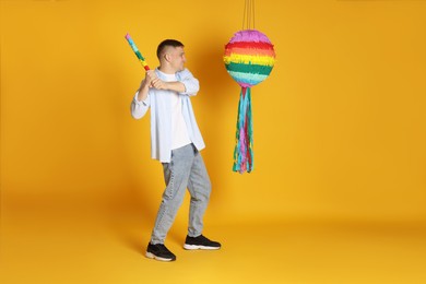 Happy man breaking pinata on yellow background