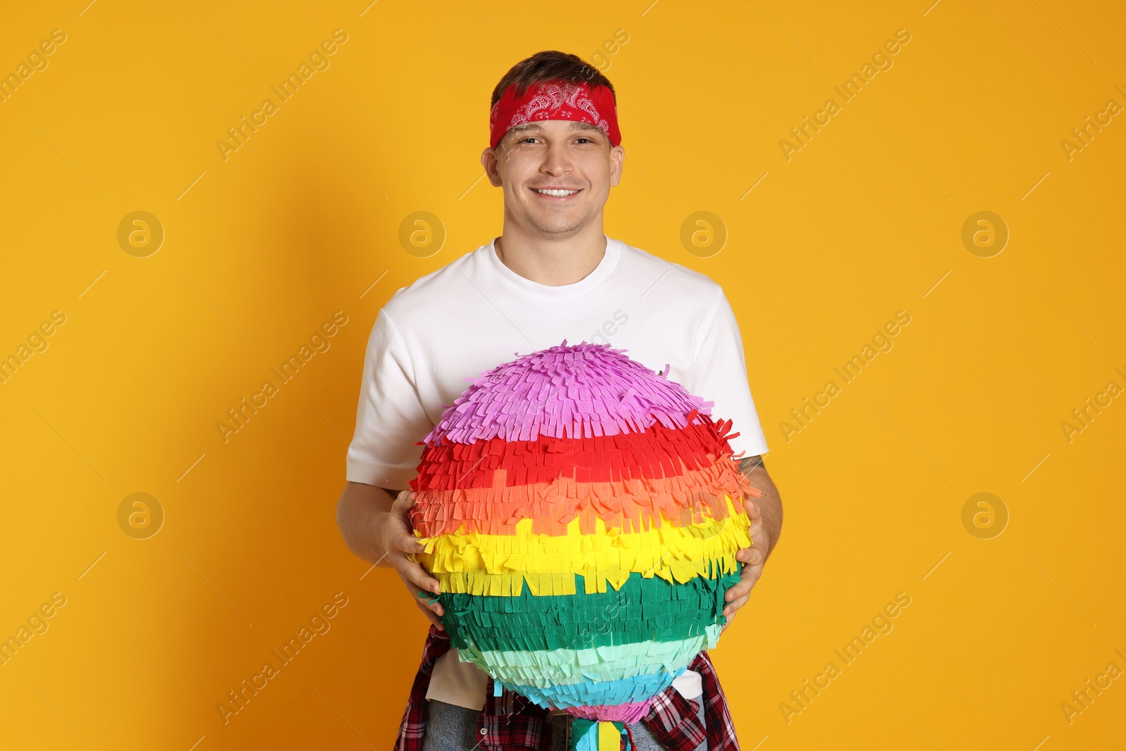 Photo of Happy man with colorful pinata on yellow background