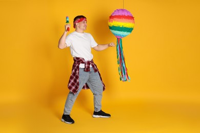 Photo of Happy man breaking pinata on yellow background