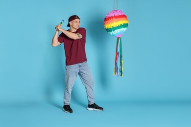 Photo of Happy man breaking pinata on light blue background