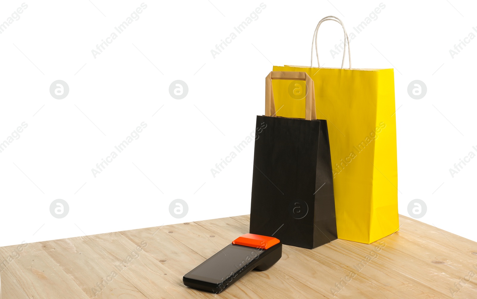 Photo of Payment terminal and shopping bags on wooden table against white background