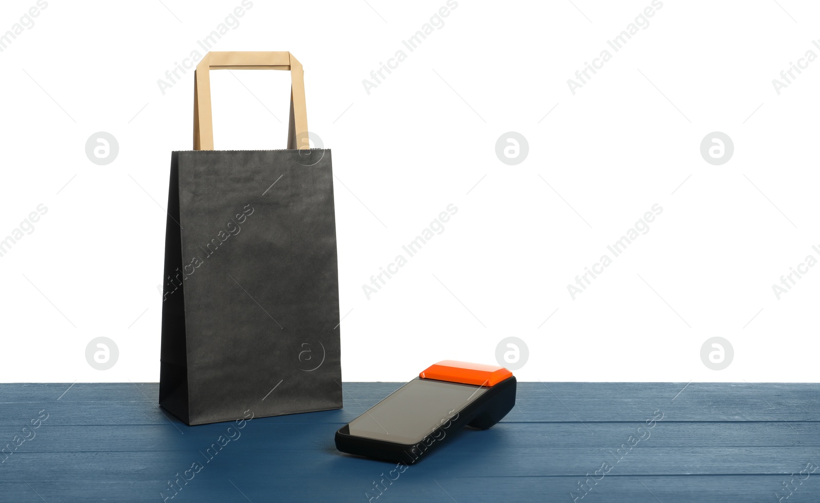 Photo of Payment terminal and shopping bag on blue wooden table against white background