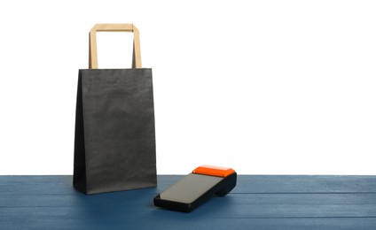 Photo of Payment terminal and shopping bag on blue wooden table against white background