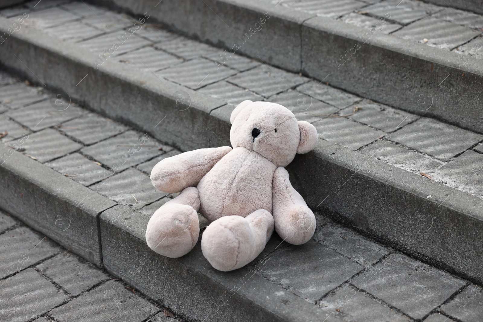 Photo of Lost white teddy bear on stairs outdoors