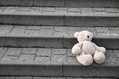 Photo of Lost white teddy bear on stairs outdoors