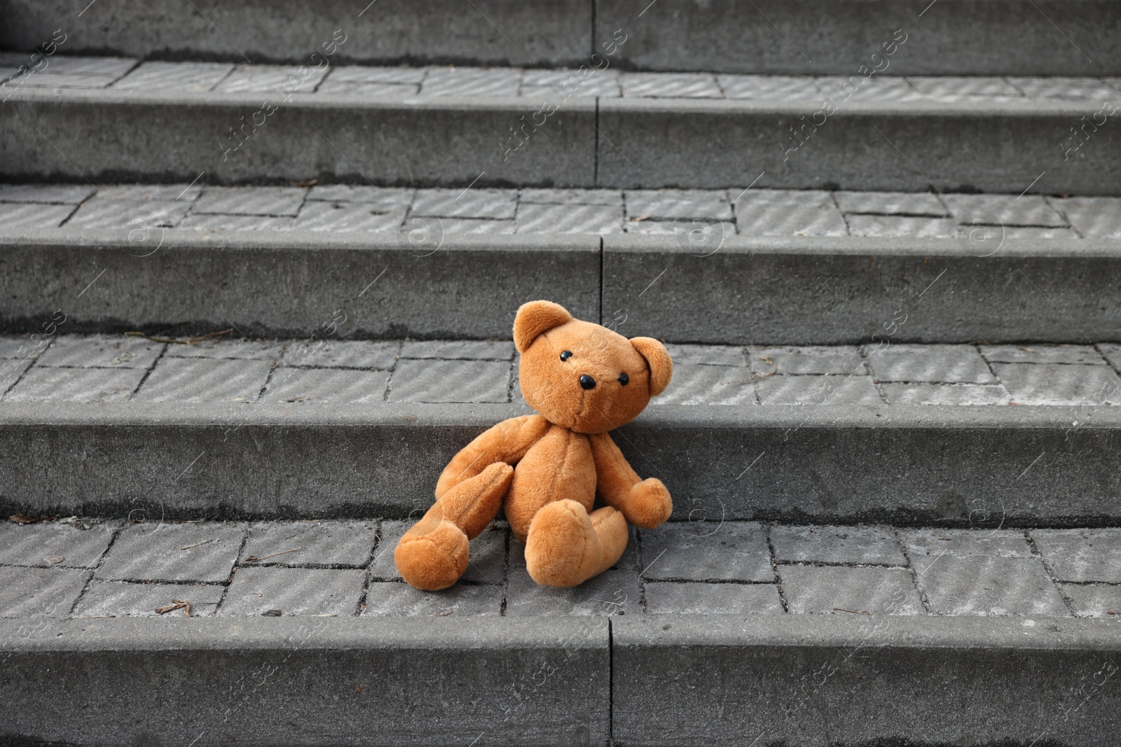 Photo of Lost brown teddy bear on stairs outdoors