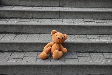 Photo of Lost brown teddy bear on stairs outdoors