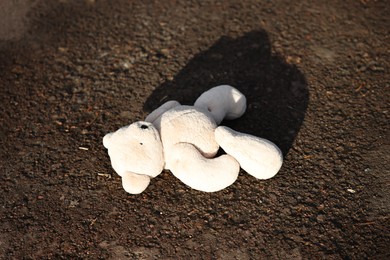 Photo of Lost white teddy bear on ground outdoors