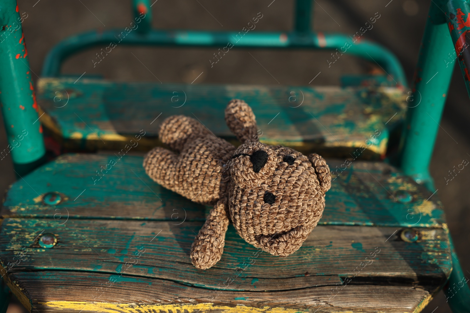 Photo of Lost knitted bear on swing outdoors, closeup