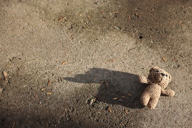 Photo of Lost knitted bear on ground outdoors, above view. Space for text