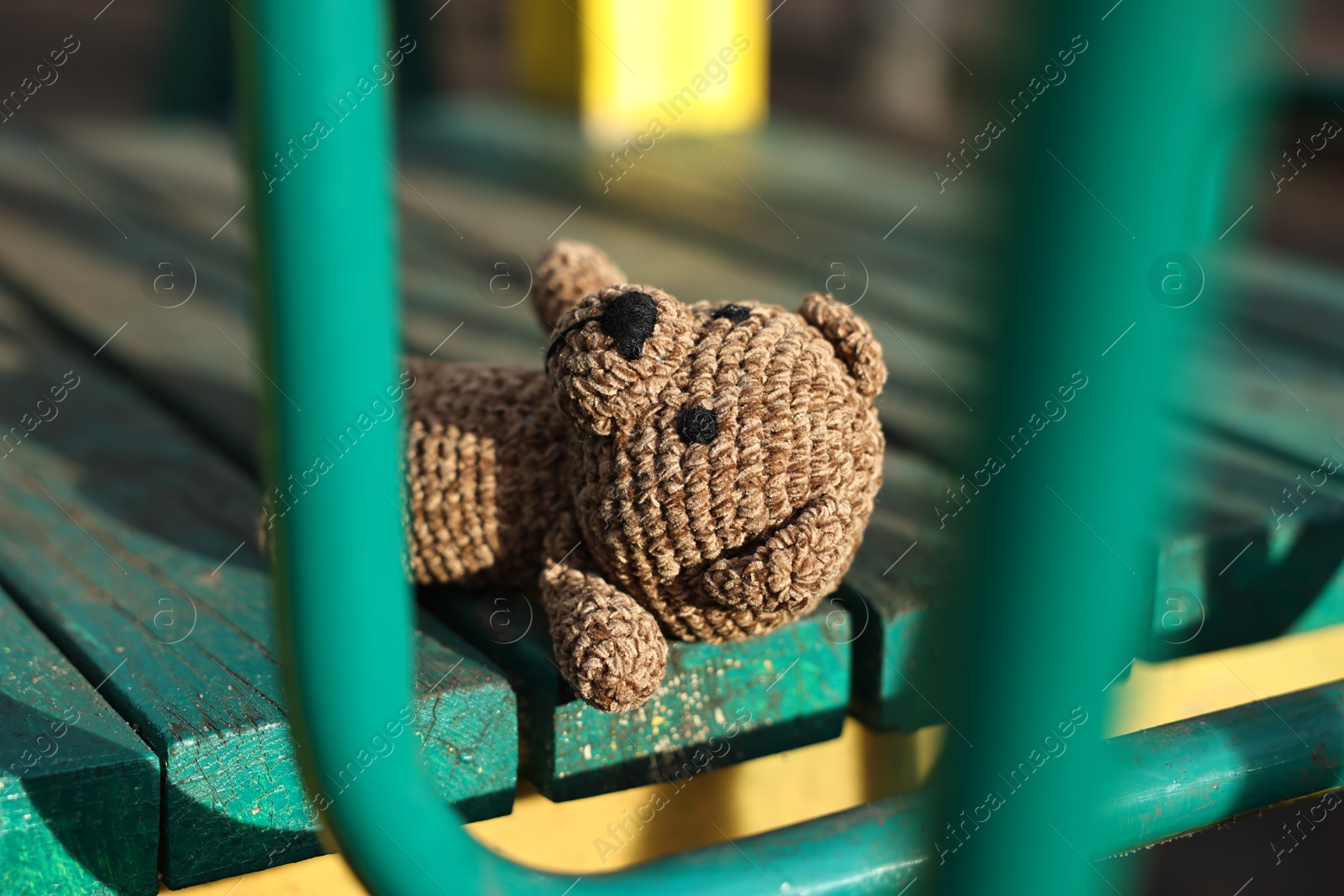 Photo of Lost knitted brown bear on playground outdoors, closeup