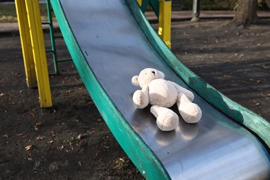 Photo of Lost white teddy bear on slide outdoors