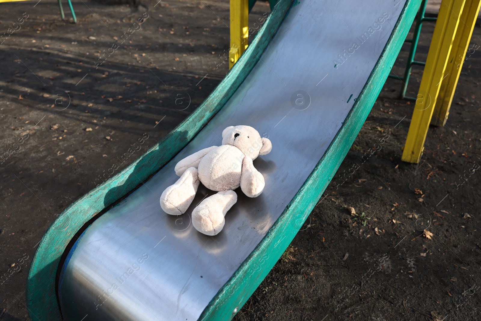 Photo of Lost white teddy bear on slide outdoors