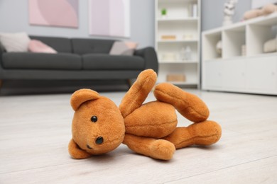 Photo of Lost brown teddy bear on floor in room, closeup