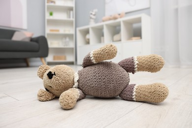 Photo of Lost knitted bear on floor in room, closeup