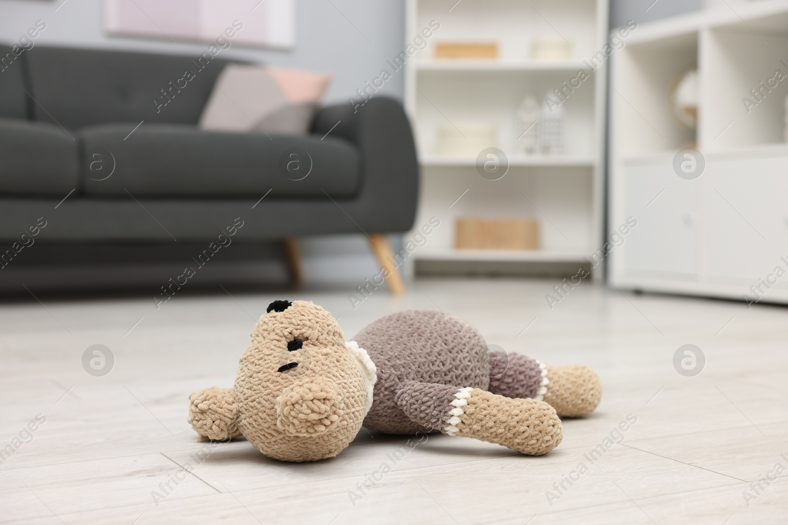 Photo of Lost knitted bear on floor in room, closeup. Space for text