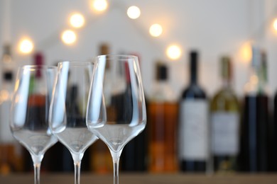 Photo of Empty wine glasses against blurred background with festive lights, closeup and space for text. Bokeh effect