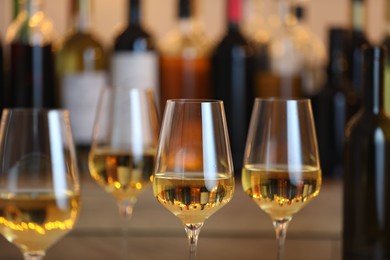 Photo of Tasty white wine in glasses against blurred background with festive lights, closeup. Bokeh effect