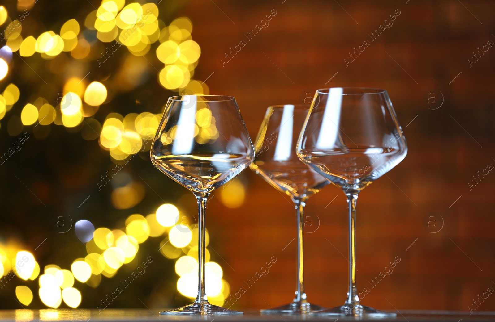 Photo of Wine glasses on table against blurred lights. Bokeh effect