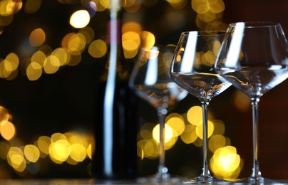 Photo of Wine glasses on table against blurred lights, space for text. Bokeh effect