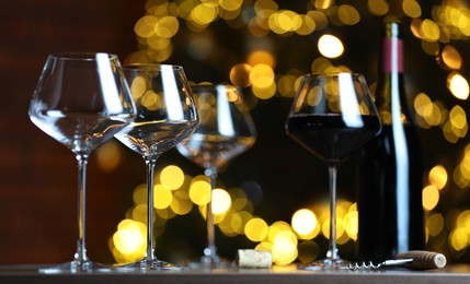 Photo of Glass with red wine and empty ones on table against blurred lights. Bokeh effect