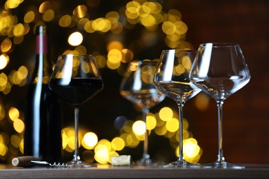 Photo of Glass with red wine and empty ones on table against blurred lights. Bokeh effect