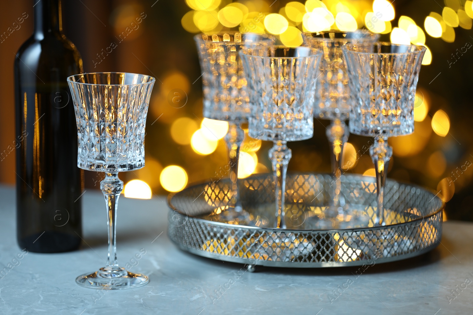 Photo of Wine in glasses and bottle on table against blurred lights. Bokeh effect