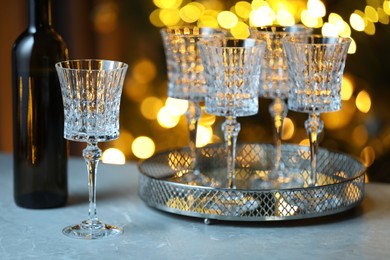 Photo of Wine in glasses and bottle on table against blurred lights. Bokeh effect