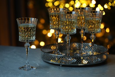 Photo of Tasty white wine in glasses on table against blurred lights. Bokeh effect