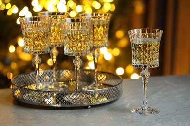 Photo of Tasty white wine in glasses on table against blurred lights. Bokeh effect