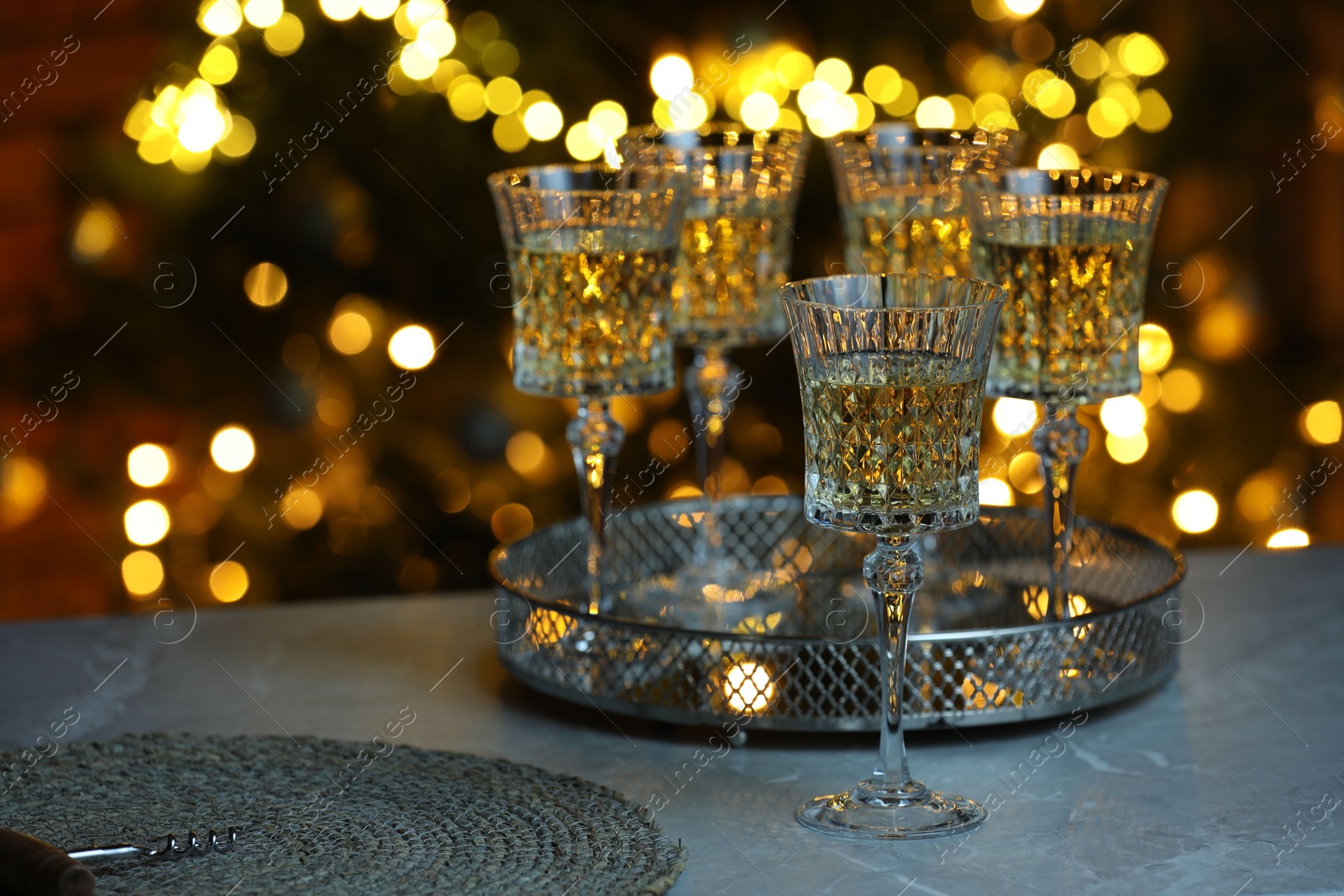 Photo of Tasty white wine in glasses on table against blurred lights. Bokeh effect