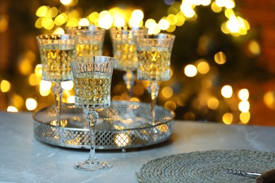 Photo of Tasty white wine in glasses on table against blurred lights. Bokeh effect