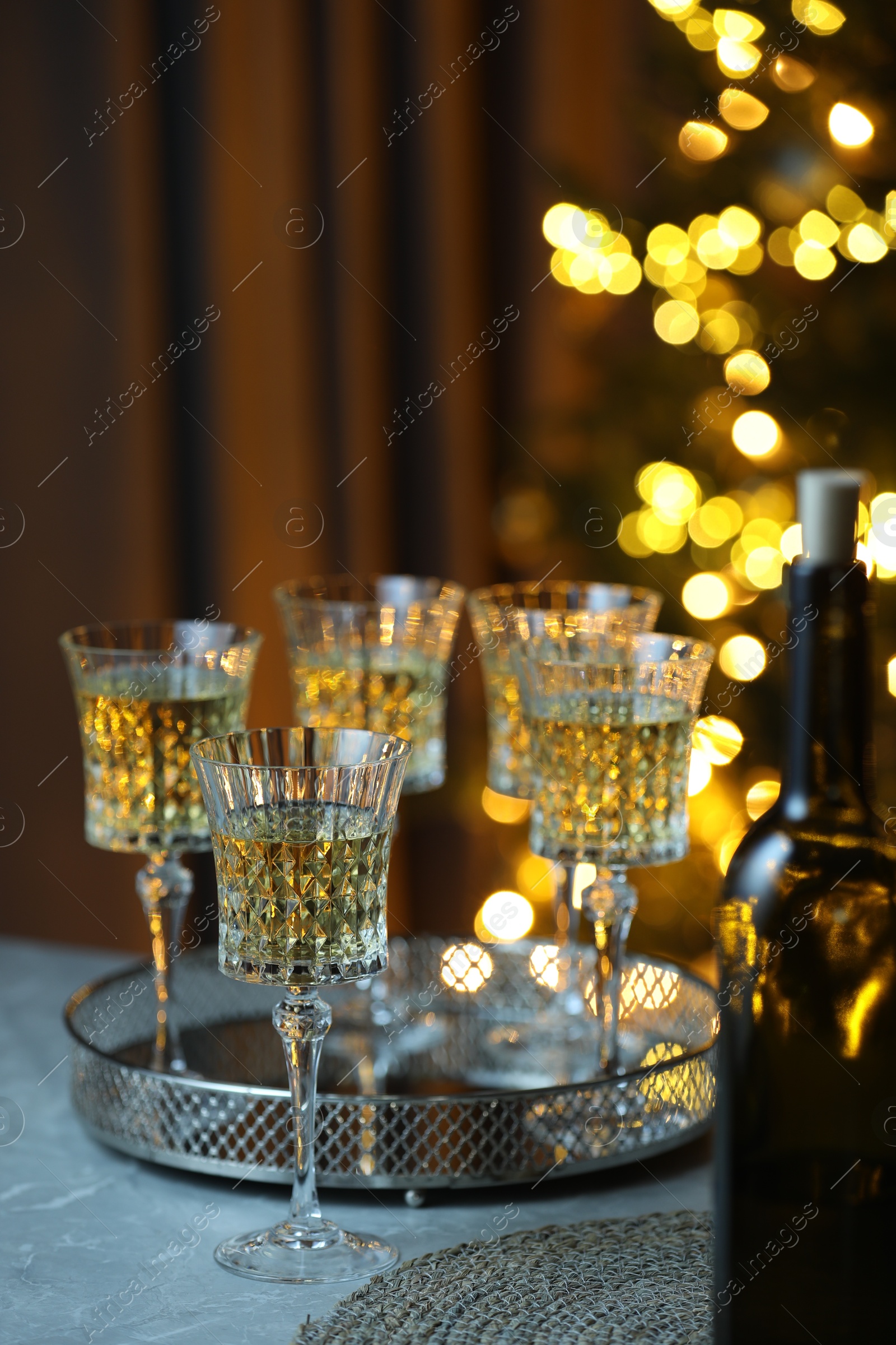 Photo of Tasty white wine in glasses on table against blurred lights. Bokeh effect